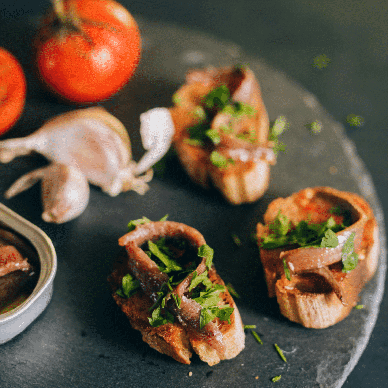 Acciughe greche su pane tostato con aglio, prezzemolo e pomodori freschi