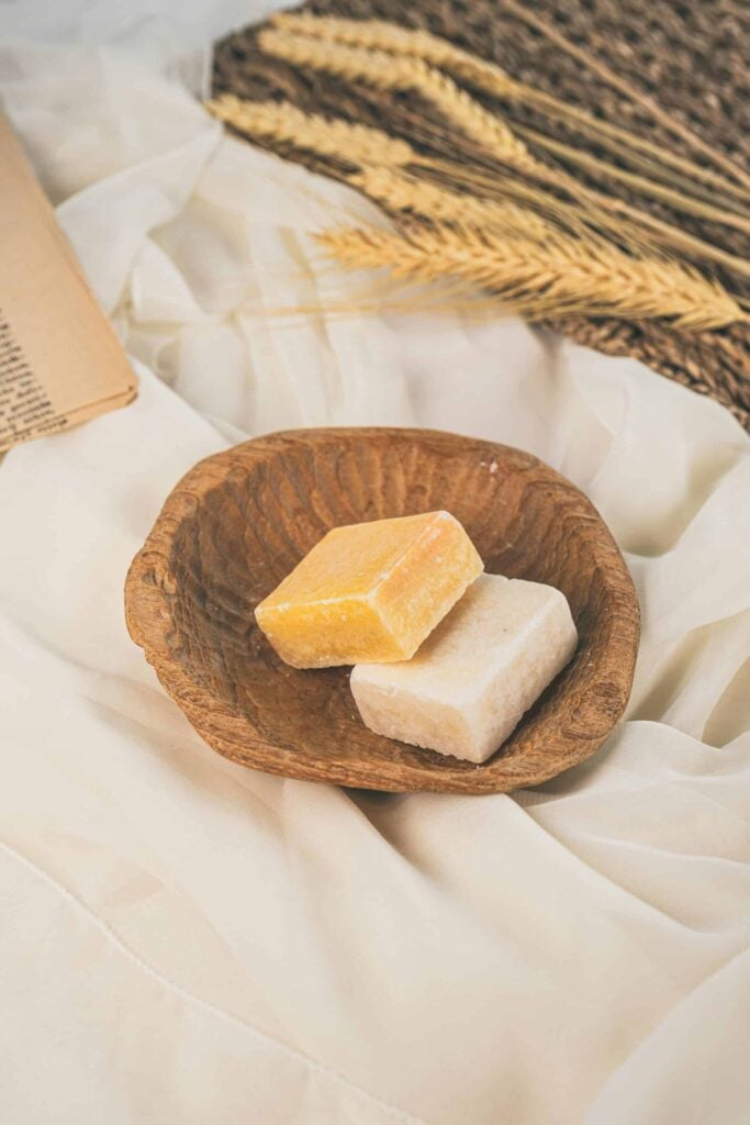 Savons grecs de différentes couleurs posés sur un plat en bois, avec des détails de texture visible.