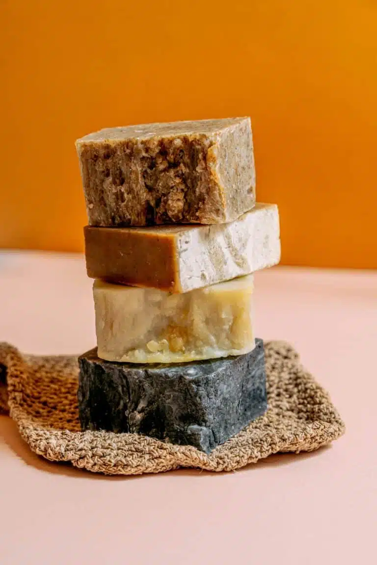 Greek soaps stacked on a beige fabric, with varied colors and distinct textures.