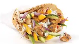 Photo of a traditional Greek Chicken Souvlaki in a white paper cone with colorful vegetables, grilled chicken and pita bread on a white background