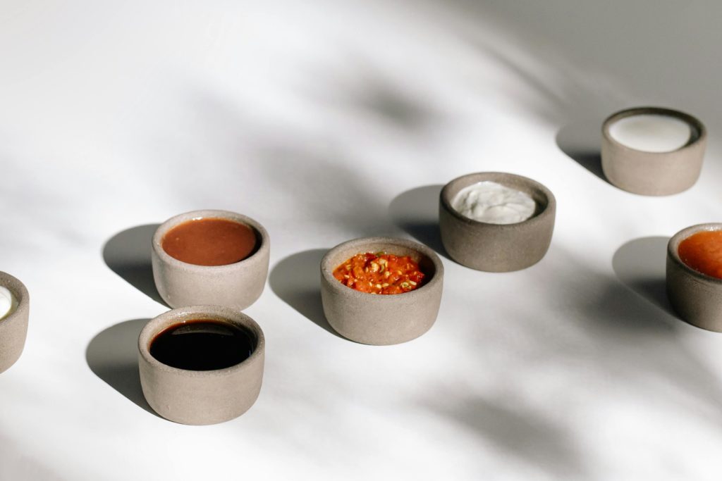 Various bowls of sauces and condiments, including Greek yoghurt, in minimalist ceramics