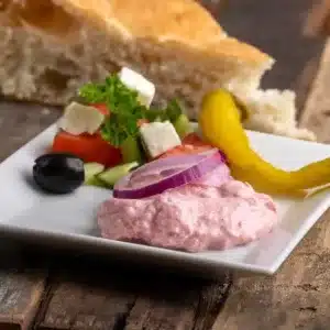 Tarama traditionnel avec tranche d'oignon, concombre, olives, feta, persil, tomate, pain grec sur table en ancien bois brut