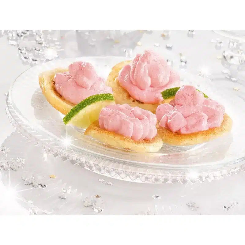 Tarama on toast with lime slices, clear glass plate, shiny star party decorations, glass table