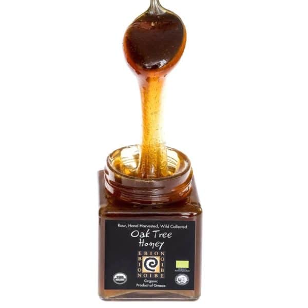 Close-up de pot de miel de chêne avec cuillère dégoulinante mettant en valeur sa texture dense