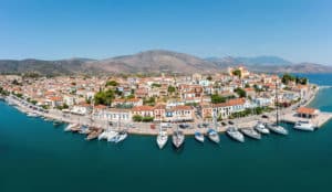 Panoramic view of a Lesbos port with white houses, pleasure boats, and mountains in the background