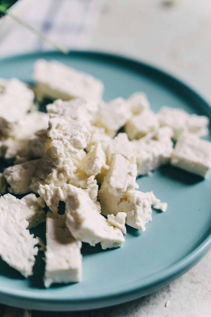 Morceaux de feta grecque traditionnelle sur une assiette turquoise.