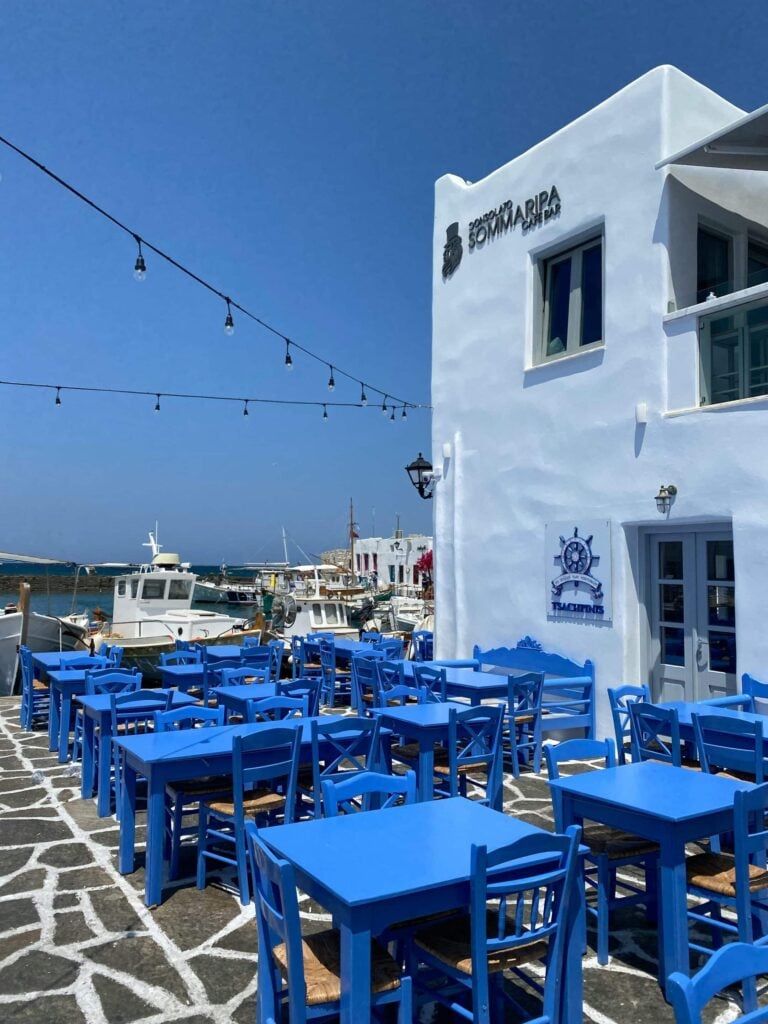 Terrasse de café traditionnelle avec chaises bleues sur le port de Paros en Grèce