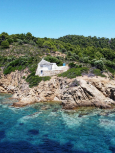 Maison blanche sur la côte rocheuse de Skiathos avec mer turquoise et végétation méditerranéenne