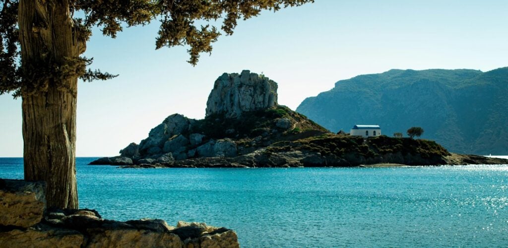 Chapelle blanche sur un îlot rocheux à Kos en Grèce, vue depuis la mer Égée