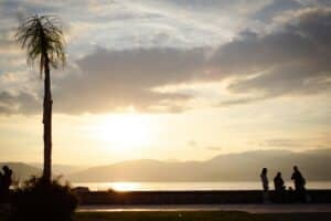 Sonnenuntergang an der Strandpromenade von Nafplio in Griechenland mit Palmen und Bergen