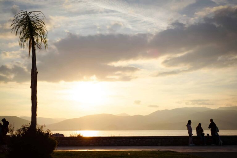 Coucher de soleil sur le bord de mer de Nauplie en Grèce avec palmiers et montagnes