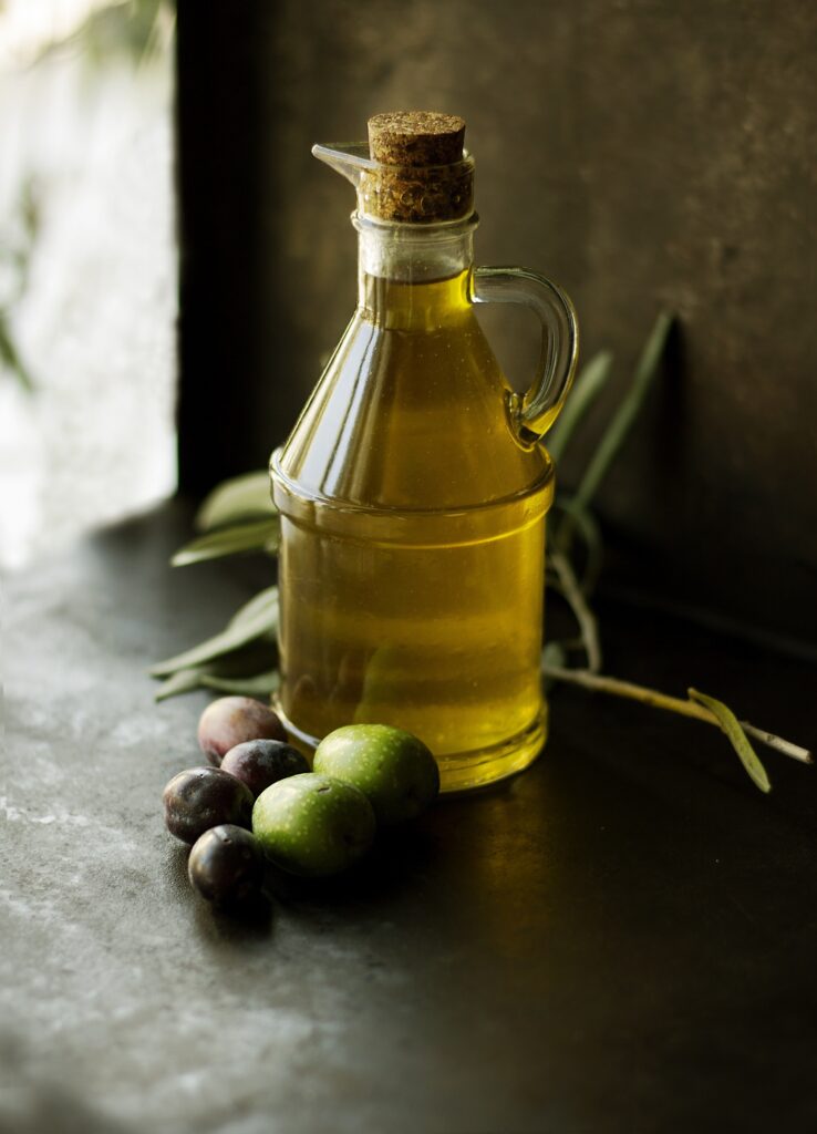 Greek olive oil in a glass bottle, with fresh green and black olives.