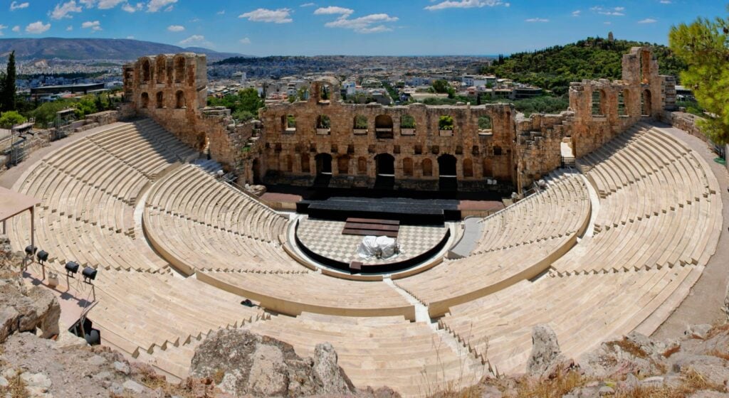 Vue panoramique de l’Odéon d’Hérode Atticus à Athènes avec les gradins en marbre et une vue sur la ville moderne.