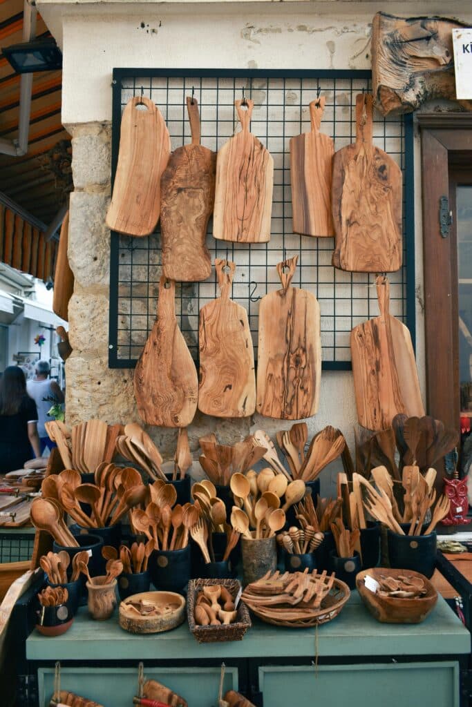 Display of Greek olive wood utensils and boards, including spoons, spatulas and cutting boards.
