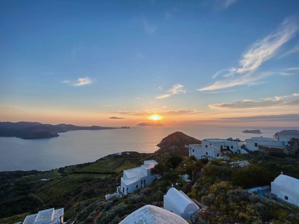 Sunset on the island of Milos seen from the heights with white houses and panoramic views over the Aegean Sea.