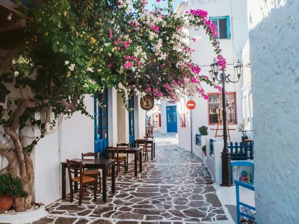 Charming flower-filled alley with bougainvillea and white houses in Milos, Greece.