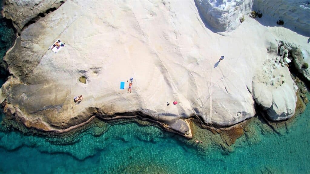 Aerial view of Sarakiniko in Milos, a beach of white rocks sculpted by wind and water, bathed by a turquoise sea.