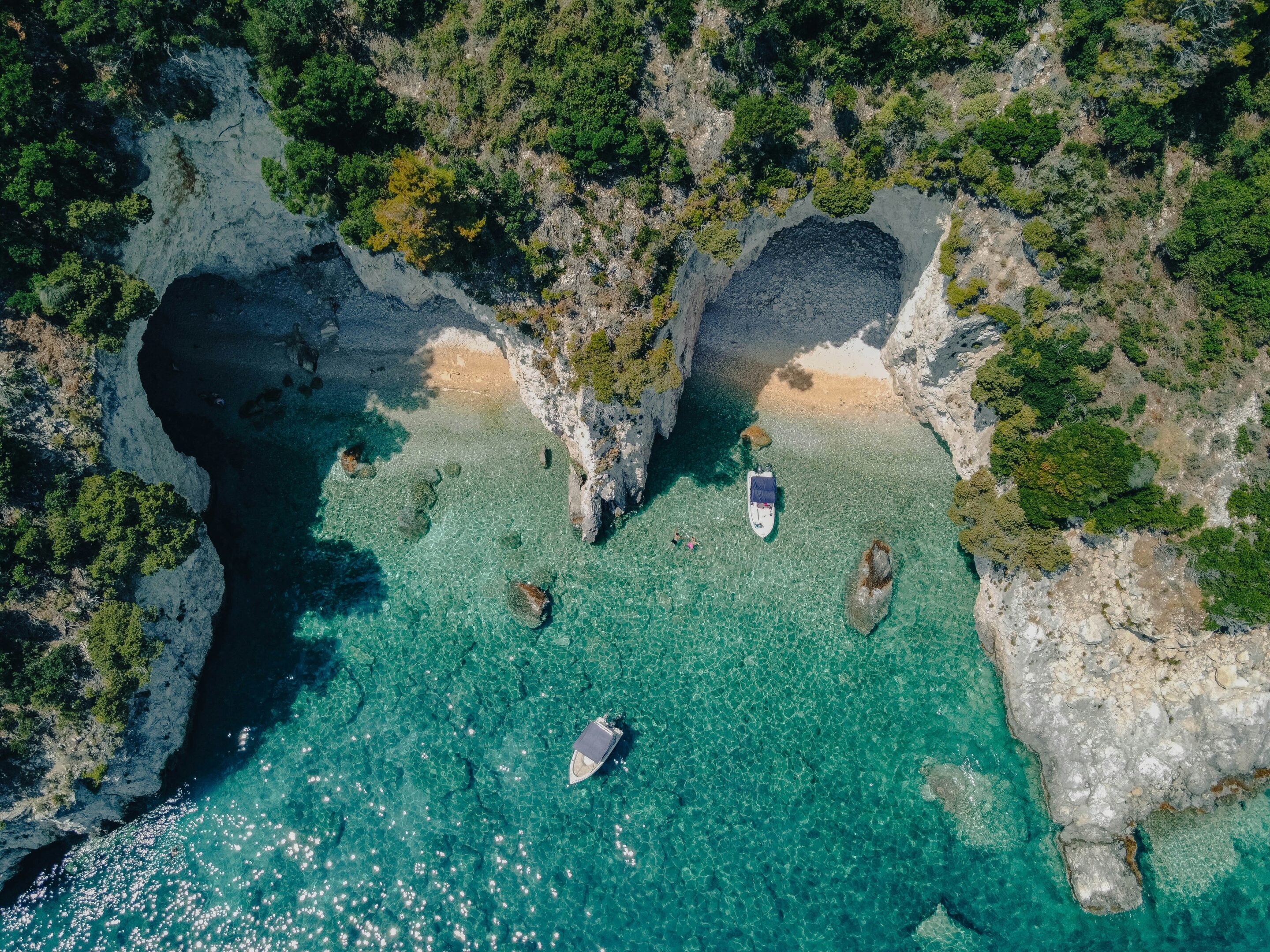 Vue aérienne d’une plage secrète à Zakynthos avec mer turquoise et petites embarcations, idéale pour visiter Zakynthos.