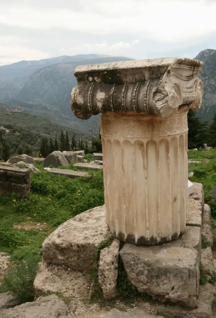 Chapiteau ionique sculpté en marbre, vestige du sanctuaire de Delphes avec vue sur les montagnes.