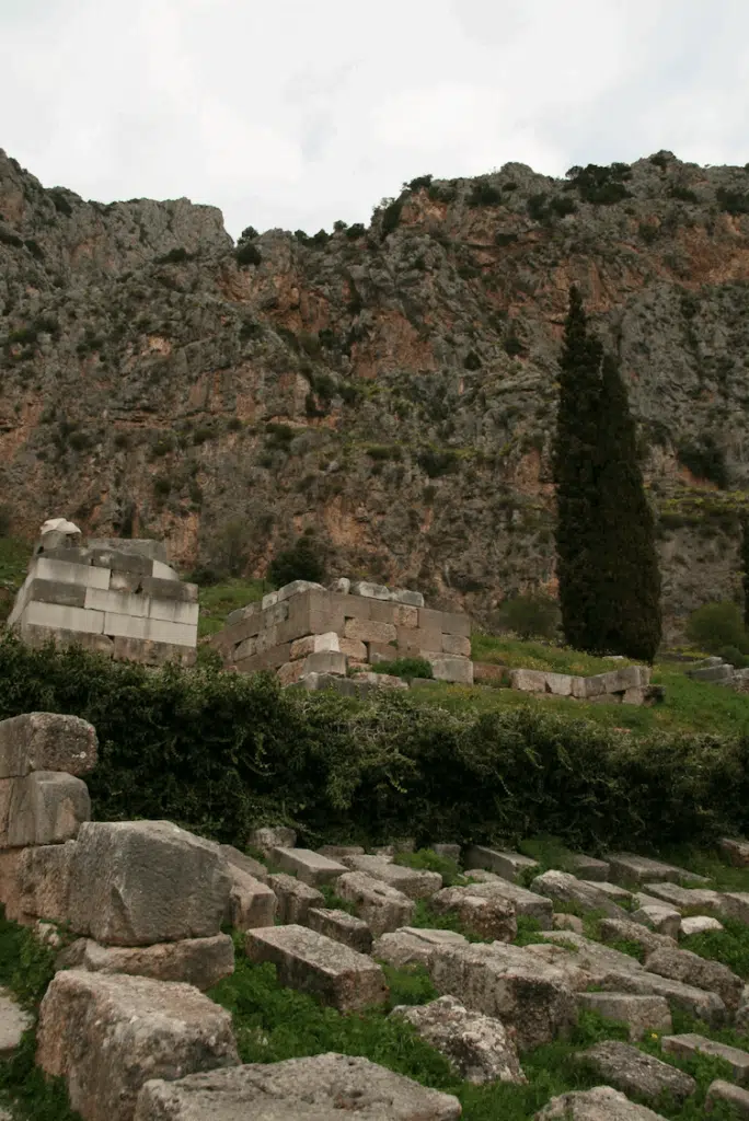 Ruines de Delphes sur fond de falaises du mont Parnasse, avec blocs antiques dispersés.
