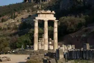 Tholos du sanctuaire d’Athéna Pronaia à Delphes, entouré de colonnes antiques et de paysages montagneux.