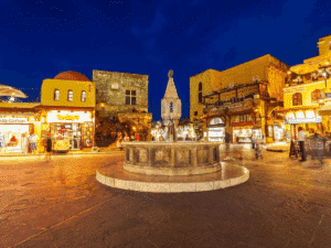 Vieille ville de Rhodes de nuit – place animée et fontaine médiévale