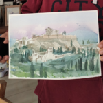 Participant tenant son aquarelle de l’Acropole durant un atelier de peinture à Athènes