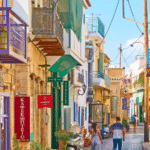 Visite à pied de la ville d'Égine en Grèce, rues traditionnelles animées avec balcons colorés et passants.