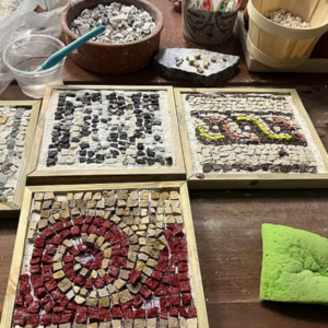 Mosaic workshop in Athens, creating colorful patterns with tesserae on a wooden support.