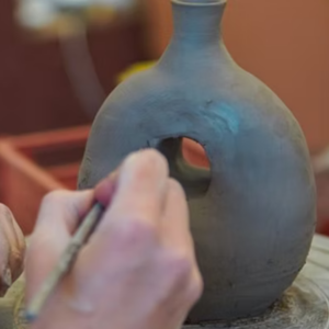 Pottery workshop in Athens, creating ceramics on a wheel with hands shaping a clay vase.