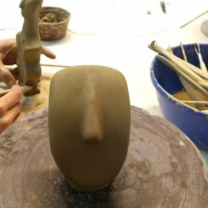 Sculpture workshop in Athens, artist working in clay on a wheel with modeling tools.