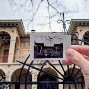 Person holding a vintage photo in front of a historic building in Athens, capturing the city's art and architecture.