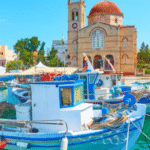 Port pittoresque de l’île d’Égine avec des bateaux colorés et l’église principale au bord de l’eau, Grèce.