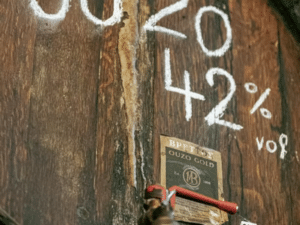 Baril d'ouzo avec étiquette Ouzo Gold et robinet de service, illustration d'une dégustation d'ouzo à Athènes.
