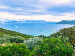 Vue panoramique sur l'île d'Égine en Grèce, avec mer turquoise, collines verdoyantes et oliveraies.