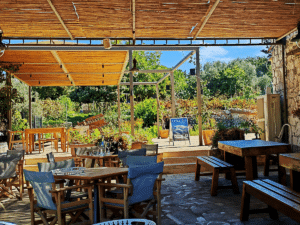 Terrasse d'un domaine viticole en Crète avec tables et chaises, illustration d'une escapade œnologique et dégustation d'huile d'olive bio.