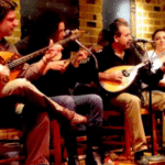 Soirée traditionnelle dans une taverne grecque avec musiciens jouant du bouzouki et du luth devant le public.