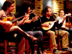 Soirée traditionnelle dans une taverne grecque avec musiciens jouant du bouzouki et du luth devant le public.