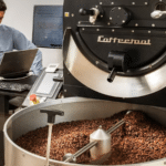 Visite d'une usine de torréfaction de café à Egine, avec un opérateur devant un torréfacteur de café professionnel.