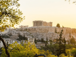 Vue de l'Acropole et du Parthénon à Athènes depuis un point de vue pittoresque, entouré de végétation.